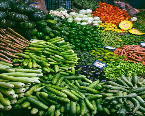 A colorful selection of fresh green avocados and seasonal organic vegetables from a local market
